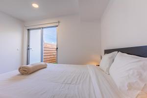 una camera bianca con un grande letto con finestra di Mare Nostrum Apartment a Ponta Delgada