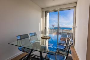 uma mesa de jantar em vidro com cadeiras e vista para o oceano em Mare Nostrum Apartment em Ponta Delgada
