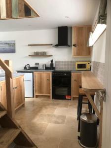 a kitchen with wooden cabinets and a black stove top oven at Cosy Rustic Annex in quiet Cornwall Village in Saint Wenn