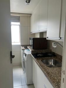 una cocina con armarios blancos y fregadero en Apartamento no centro de Curitiba,bem localizado e confortável, en Curitiba
