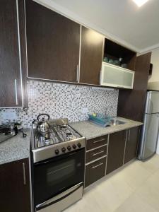 a kitchen with brown cabinets and a stove top oven at Departamento Rivadavia in Mar del Plata +5 photos
