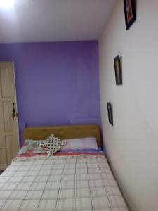 1 dormitorio con 1 cama con pared morada en Hotel tanta Wasi, en Quito