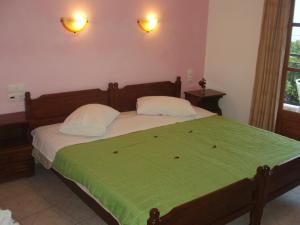 1 cama con 2 almohadas y manta verde en SKIATHOS STUDIOS en Skíathos