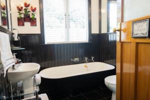 a bathroom with a tub and a toilet and a sink at Gumnut House. in Whanganui