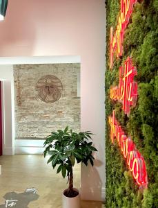 una pianta in una stanza con un muro con insegne al neon di XENIA LUXURY ROOMS a Reggio di Calabria
