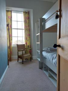 a bedroom with a bunk bed and a chair and a window at Laston House in Ilfracombe