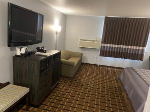 a hotel room with a flat screen tv and a couch at Faribault Hometown Inn & Suites in Faribault