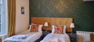 two beds in a room with green wallpaper at Laston House in Ilfracombe