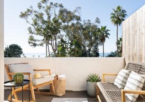 a patio with chairs and a table and palm trees at Laguna Beach Lodge in Laguna Beach