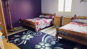 - une chambre avec 2 lits et un mur violet dans l'établissement القاهره, au Caire