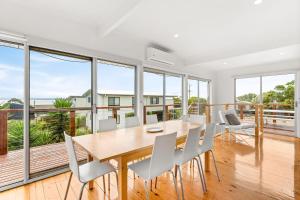 a dining room with a table and chairs and large windows at Sea to Sunset View in Ventnor