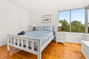 a white bedroom with a bed and a window at Sea to Sunset View in Ventnor