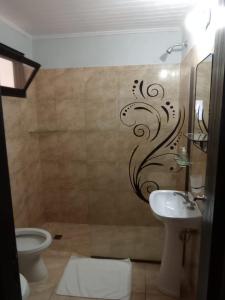 uma casa de banho com um lavatório, um WC e uma parede em La casita em Porto Iguaçu
