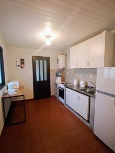 uma cozinha com armários brancos, um lavatório e um frigorífico em La casita em Porto Iguaçu