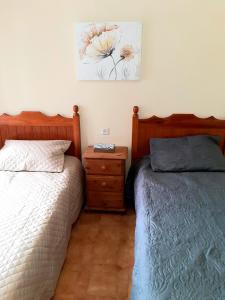 a bedroom with two beds and a nightstand and a painting at Beachfront Penthouse 3 double bedrooms, 2 bathrooms in San Luis de Sabinillas