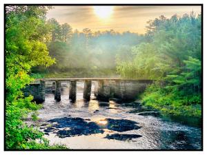 a bridge over a river with trees in the background at Sewall House Yoga Retreat in Island Falls