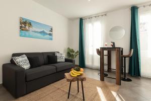 a living room with a black couch and a table at Sweet Aloha - Le Mourillon -Host in Toulon
