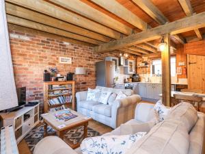 uma sala de estar com dois sofás e uma parede de tijolos em The Dairy Barn em Fakenham