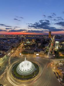 Eine Stadt leuchtet nachts mit einem Brunnen in der Unterkunft Slavija McD apartment in Belgrad