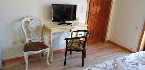 a bedroom with a desk with a tv and two chairs at VianasHome in Amarante