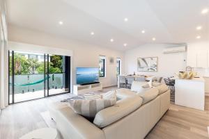 a living room with a white couch and a kitchen at Beach Haven 3a Messines Street 4 Minute walk to the beach Wifi Air Con in Shoal Bay