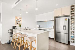 Penthouse Bridgeview San Remo في سانريمو: مطبخ مع دواليب بيضاء وجزيرة مطبخ مع الكراسي