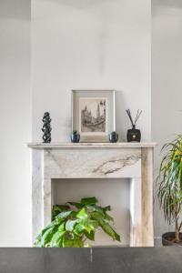 a living room with a white fireplace with plants at Luxurious modern apartment in Antwerp - Breakfast Included in Antwerp