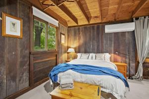 a bedroom with a bed and a wooden wall at NUNGAROO COTTAGE in Bilpin