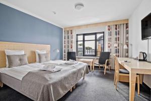 una camera d'albergo con letto, scrivania e tavolo di Hotel Svendborg a Svendborg