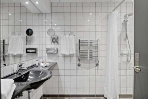 un bagno piastrellato bianco con lavandino e doccia di Hotel Svendborg a Svendborg