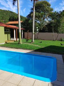 a swimming pool in front of a house with palm trees at Tiny House Perfeita para Casais in Florianópolis