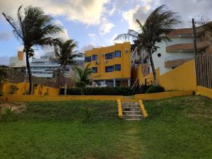 un edificio amarillo con palmeras frente a un patio en Atlântico Flat -207- Vista ao Mar e Pé na Areia, en Natal