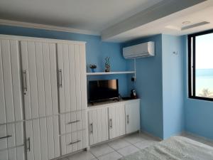 a blue room with white cabinets and a television at Atlântico Flat -207- Vista ao Mar e Pé na Areia in Natal
