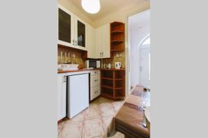 ブダペストにあるComedy Apartmentの白いキャビネットとテーブル付きのキッチンが備わります。