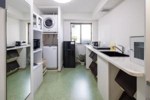 cocina con encimeras blancas y nevera negra en Granrina Kanazawa - Female only apartment hotel, en Kanazawa