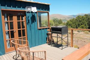 una terraza con parrilla y sillas en una casa en Cuatro Vientos Patagonia - Lago Huechulafquen en Junín de los Andes