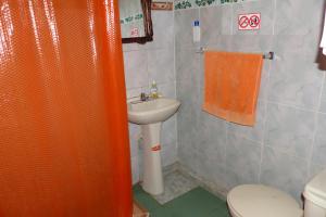 Hostal La Casa Amarilla City في بانوس: حمام مع ستارة دش برتقالية ومغسلة