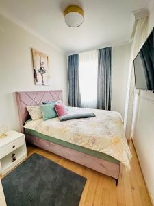 a bedroom with a bed with a pink headboard and a window at Stan na dan "Apartman Purple" in Banja Luka