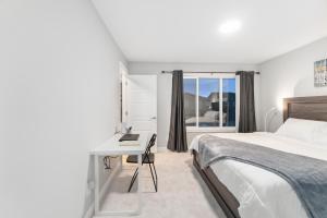 een slaapkamer met een bed, een bureau en een raam bij Upscale Urban Oasis- Stylish Townhome Getaway-Comfort for Family, Work and Longer Visits in Edmonton
