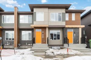 a house with orange doors and snow in front of it at Upscale Urban Oasis- Stylish Townhome Getaway-Comfort for Family, Work and Longer Visits in Edmonton