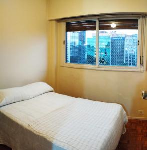 1 dormitorio con cama blanca y ventana en METROBUS OBELISCO blue venta en Buenos Aires