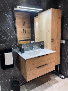 ein Badezimmer mit einem weißen Waschbecken und Holzschränken in der Unterkunft Appartement bord de mer avec piscine in Saint-Laurent-du-Var