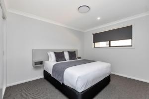 a white bedroom with a bed and a window at CH Boutique Apartments The Ringers Road in Tamworth