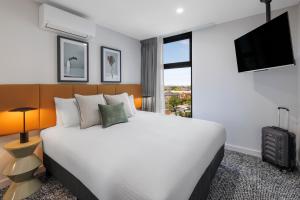 um quarto de hotel com uma cama grande e uma janela em Punthill Essendon North em Melbourne