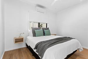 a white bedroom with a large bed with green pillows at Port Lincoln Beachfront Apartments in Port Lincoln