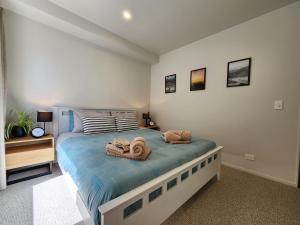 a bedroom with a bed with towels on it at Coastal Living in Comfort in Raglan