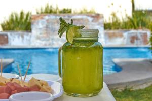 un frasco de líquido verde junto a un plato de comida en Hotel del Alba Inn & Suites, en Aguascalientes