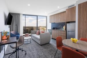 an apartment living room with a couch and a kitchen at Punthill Essendon North in Melbourne