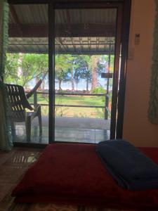 a bedroom with a bed and a chair and a window at Sukorn Andaman Beach Resort in Ko Sukon