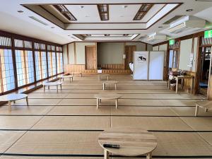 uma grande sala com mesas, bancos e janelas em 津川温泉 清川高原保養センター em Aga